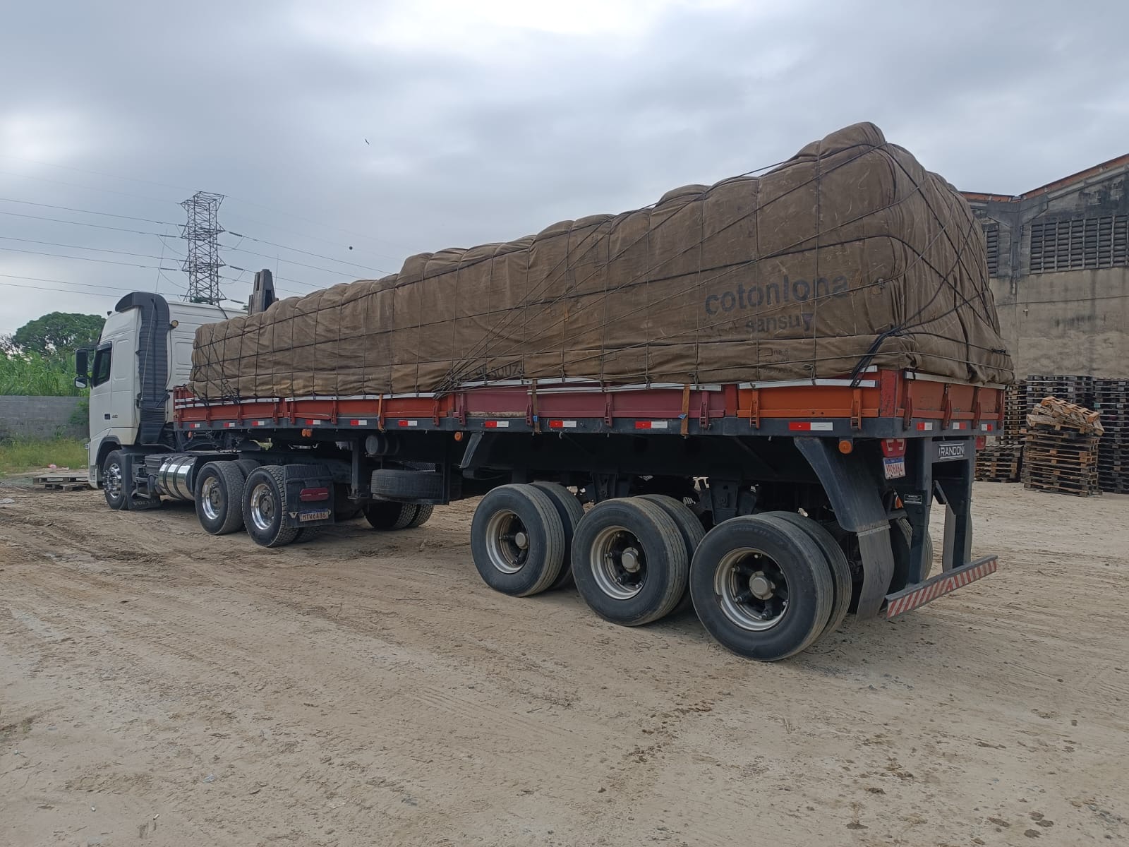 Carreta com carga enlonada e amarrada no pátio